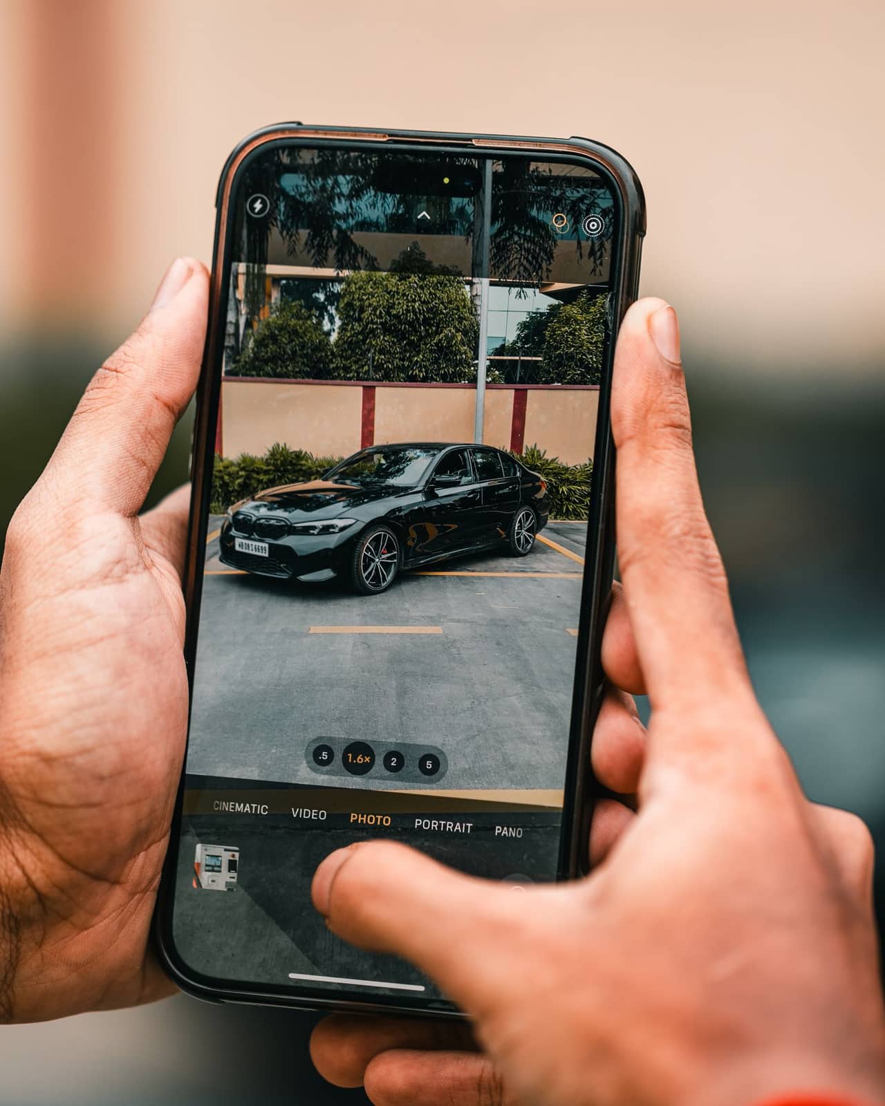 Zwei Hände fotografieren eine schwarze Limousine mit dem Smartphone – das Inserat entsteht direkt am Fahrzeug