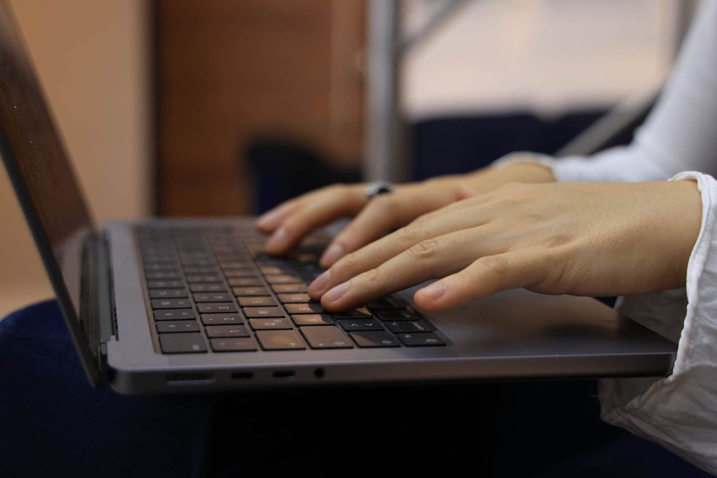 Hände tippen auf der Tastatur eines aufgeklappten Laptops