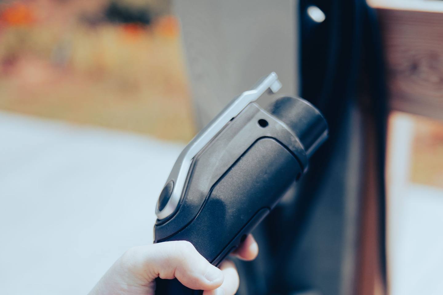 Eine Hand hält den Ladestecker eines Elektrofahrzeugs