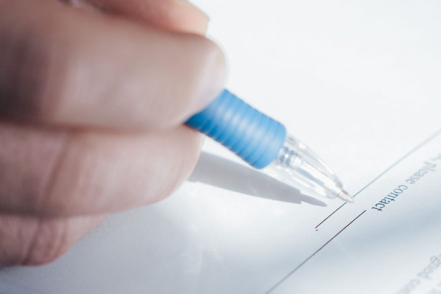Eine Hand setzt einen Kugelschreiber auf die Unterschriftszeile eines Papiers