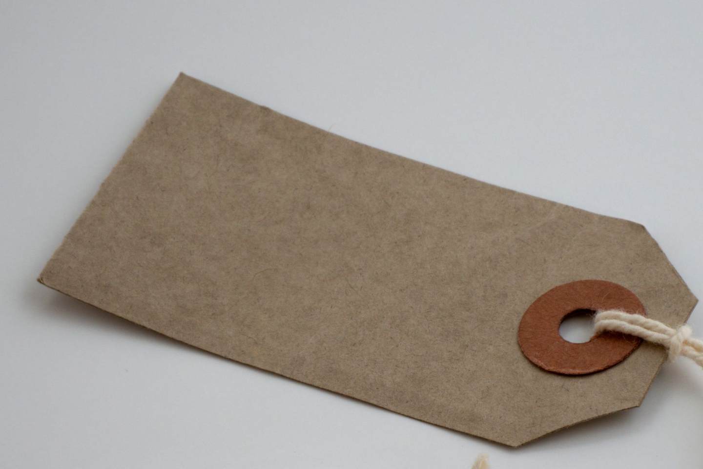 Leerer Anhänger aus braunem Papier mit Schnur auf heller Fläche